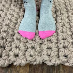 the feet of a person wearing pink and grey socks on a gray crocheted blanket