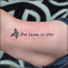 a woman's arm with the words she lives in you tattooed on it