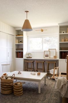 a living room filled with furniture and lots of storage space next to a white table