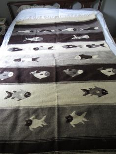 a bed covered in a blanket with fish and skulls on the bottom, next to a night stand