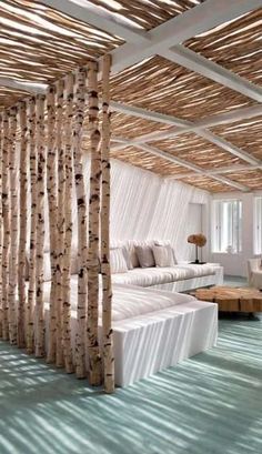 a living room filled with white furniture and lots of birch trees in the ceiling area