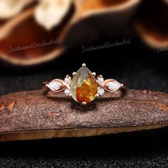 an orange and white diamond ring sitting on top of a piece of wood