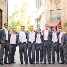 a group of men standing next to each other in front of a brick building wearing suits and ties