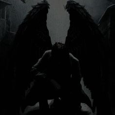 an angel kneeling down in the dark with his wings spread