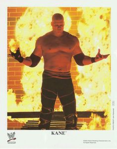 an autographed wrestler standing in front of a fire with his arms outstretched and hands out