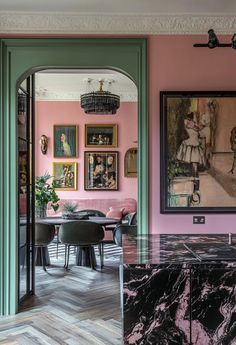 a dining room with pink walls and green trim on the wall, marble counter top