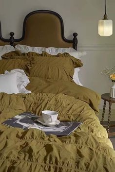 a bed that has some pillows on it and a coffee cup sitting on the pillow