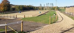 an empty horse paddock in the middle of a dirt and grass area with fencing around it