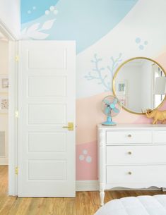 a white dresser sitting in front of a mirror on top of a wooden floor next to a wall