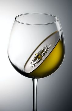 a close up of a wine glass with white wine in it's bottom half