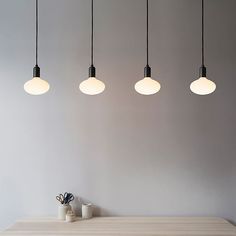 four lights hanging from the ceiling above a table