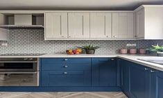 a kitchen with blue and white cabinets, an oven, sink and dishwasher