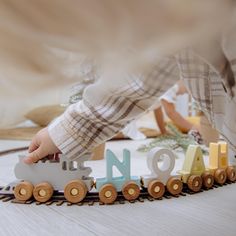 a child's hand touching the letters on a toy train