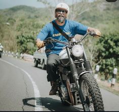 a man riding on the back of a motorcycle down a road