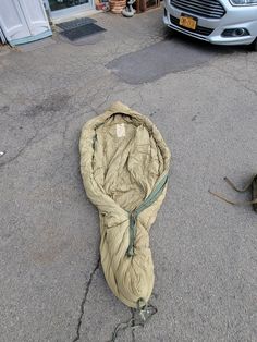 a sleeping bag on the ground next to a car