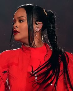 a woman with long black hair wearing a red dress and earrings on stage at an event