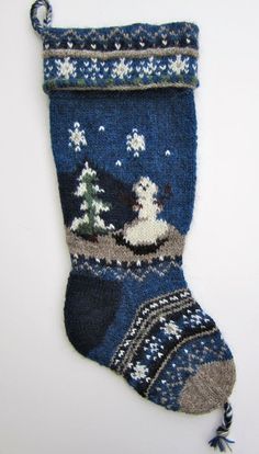 a knitted christmas stocking hanging on a wall with snowflakes and trees