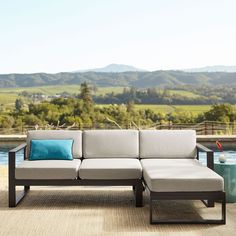 a couch sitting on top of a wooden floor next to a pool with mountains in the background