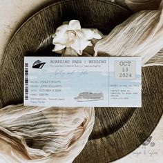 a boarding pass sitting on top of a wooden plate next to a flower and cloth