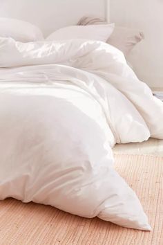 an unmade bed with white sheets and pillows