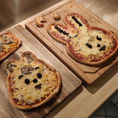 three pizzas with different toppings sitting on wooden cutting boards next to each other