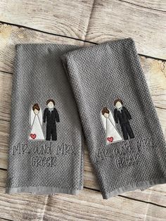 two gray towels with embroidered bride and grooms on them