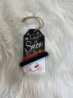 a snowman ornament hanging on a white furnishing with the words let it snow