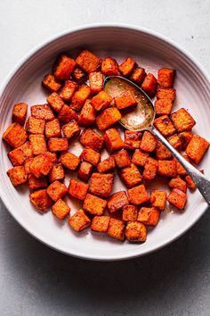 a white bowl filled with cooked sweet potatoes and a spoon on top of the bowl