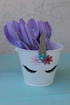 a white bucket filled with purple plastic spoons