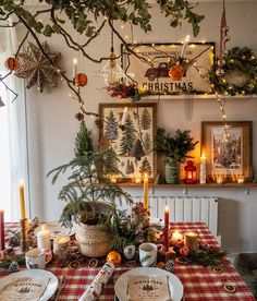 a dining room table set for christmas with candles, plates and decorations on the wall