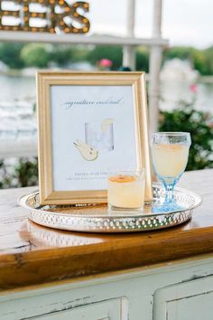 a table with a framed photograph and two glasses on it