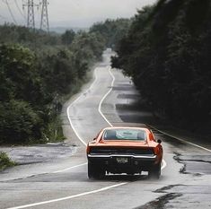 an orange car is driving down the road