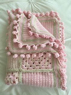 a crocheted blanket with pink and green trim