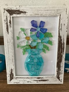 a glass vase with flowers in it sitting on a table next to a blue candle holder