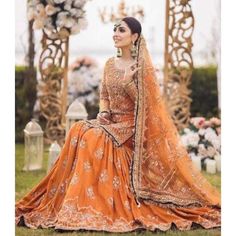 a woman in an orange lehenga sitting on the grass