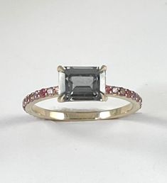 Cast in 18k white gold. A stunning gunmetal grey spinel gemstone faceted in a traditional emerald cut set in sharp stylized prongs. The band is cast in 18k white gold and features multi shade pink sapphire accent stones. - 18k white gold - .88ct emerald cut grey spinel - .33ctw pink purple sapphires Available in 18k white, 18k yellow and 18k rose gold inquire for platinum pricing. Most CM pieces can be made to order with alternate gemstones. Please inquire at cm@carlamorrison.com This Carla Morr Modern Emerald Cut Sapphire Ring With Accent Stones, Emerald Cut Pink Sapphire Ring In Fine Jewelry Style, Fine Jewelry Emerald Cut Pink Sapphire Ring, Emerald Cut Sapphire Ring With Rose Cut Diamonds, Emerald Cut Ruby Ring With Rose Cut Diamonds, Emerald Cut Pink Sapphire Ring, Spinel Gemstone, Pink Sapphire Ring, Purple Sapphire