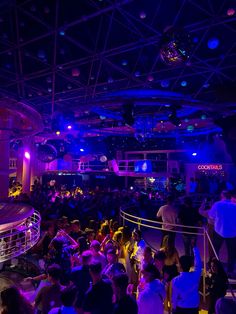 a group of people standing around in a room with lights on the ceiling and disco balls hanging from the ceiling