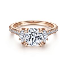 a rose gold engagement ring with two round diamonds on the band and an oval center stone