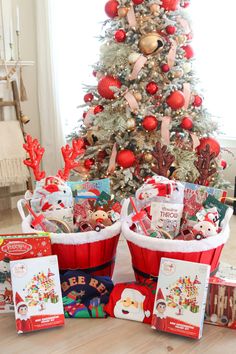 a christmas tree is decorated with red and white baskets filled with holiday gifts for children