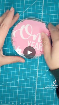 someone is cutting out a pink cake with the words one year written in white on it