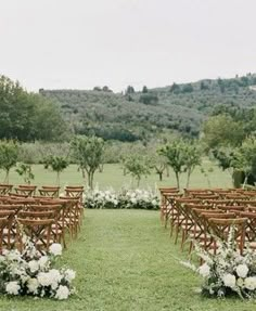 an outdoor ceremony set up with wooden chairs and flowers