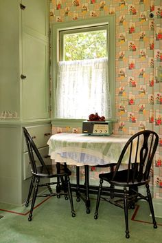 two chairs at a table in front of a wallpapered room with a window