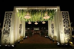 the entrance to an outdoor wedding venue decorated with greenery and hanging chandeliers