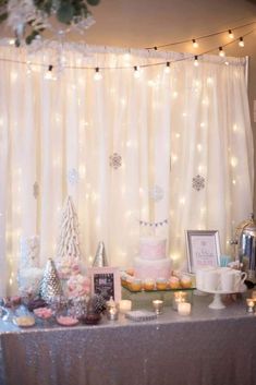 a table topped with cakes and cupcakes next to a window covered in lights