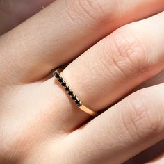 a woman's hand with a gold band and black diamond ring on her finger