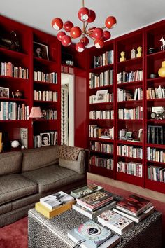 a living room filled with lots of red bookshelves and a couch next to a coffee table