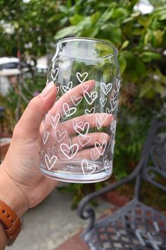 a person holding up a glass with hearts drawn on it