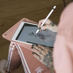 a woman is drawing on an ipad with a pencil