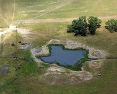 an aerial view of a pond in the middle of a field