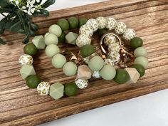 green and white beaded bracelet on wooden board next to potted plant with flowers